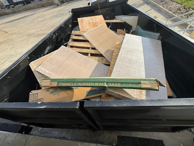 Dump trailer loaded with cardboard, rubber wall base and plywood from an Austin jobsite