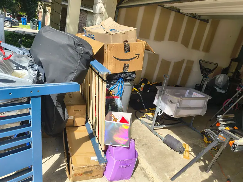 Garage packed with boxes, a crib, a workbench, tools and storage bins before a garage cleanout