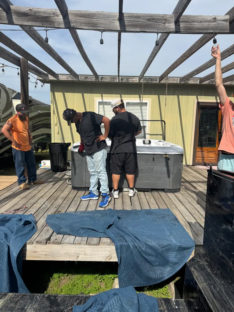 Crew assessing a hot tub under a pergola with tarps down to protect the decking