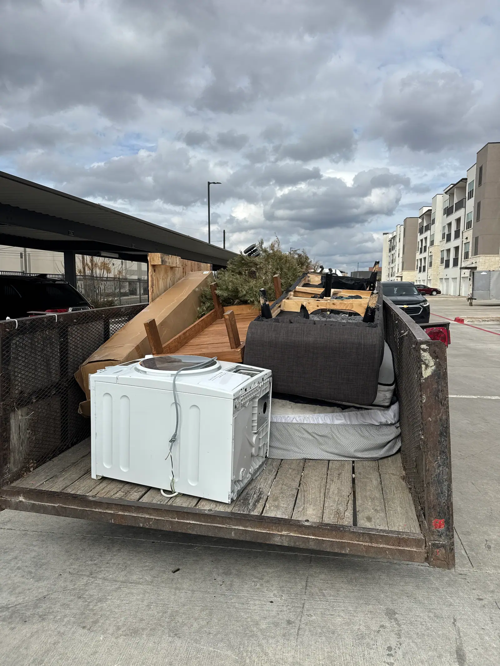 Dump trailer loaded with a washer, dryer, sectional and mattress after a Kyle property cleanout