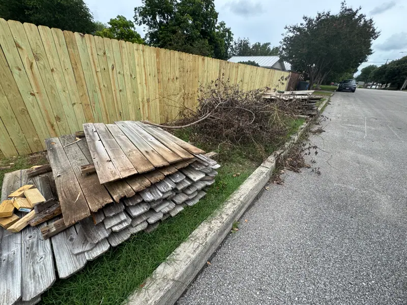 New cedar fence in New Braunfels with the old pickets and brush stacked at the curb for haul off
