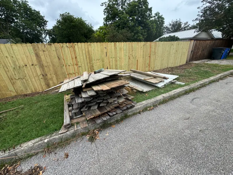 Street view of a New Braunfels fence removal with debris stacked for pickup