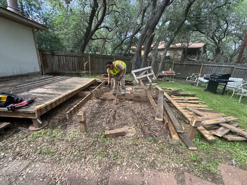 Crew member prying deck boards off the framing during a San Marcos deck removal