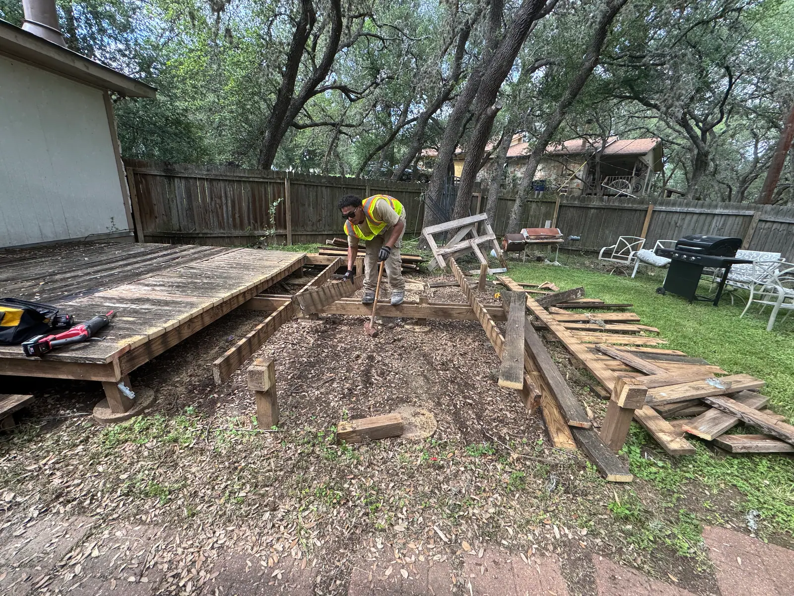 Crew member prying deck boards off the framing during a San Marcos deck removal