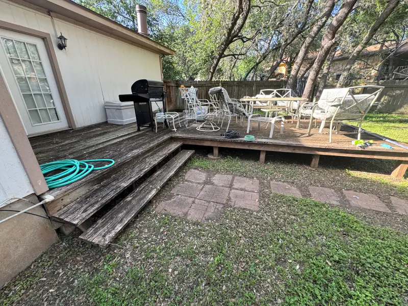 Weathered backyard deck in San Marcos before demolition, patio furniture still on the boards