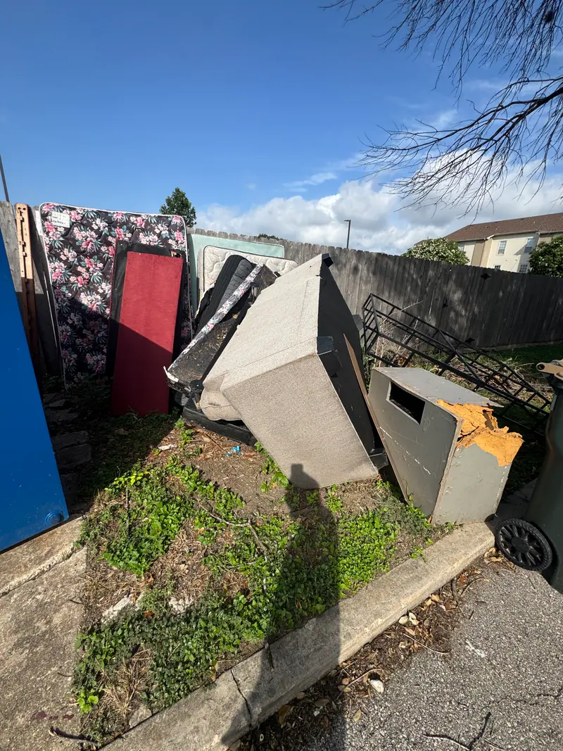 Wider view of the San Marcos curbside pile with sectional cushions and cardboard