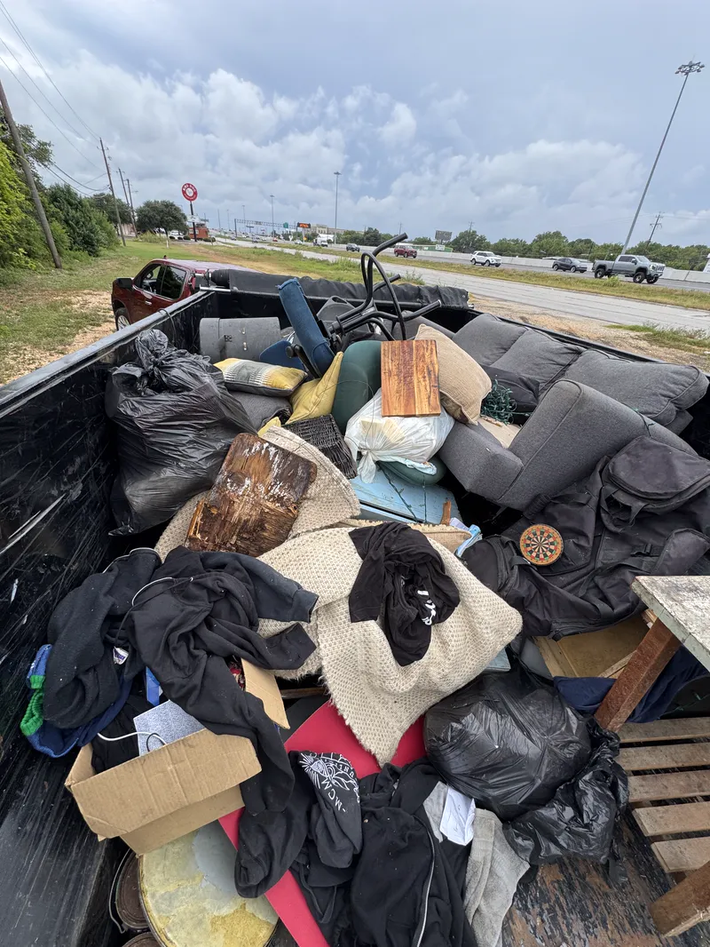 Dump trailer packed with couches, cushions, bagged waste and household goods on a full load