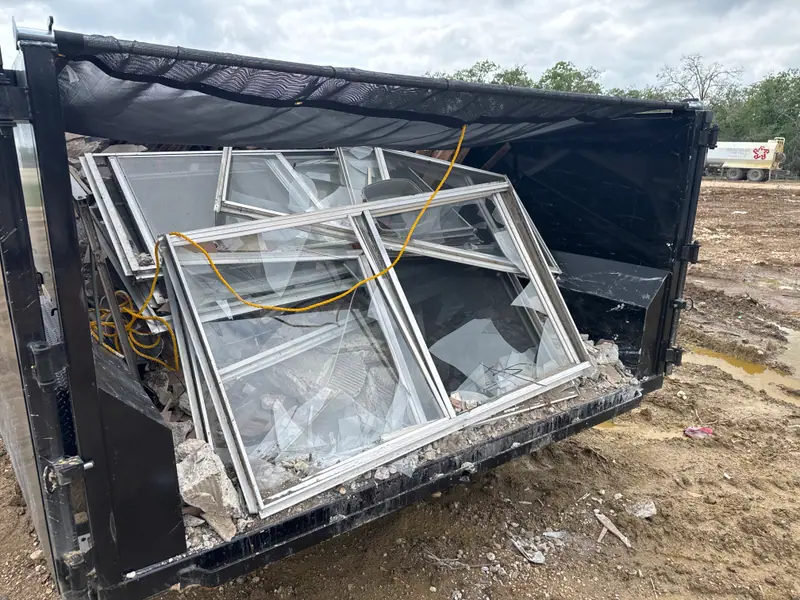 Old aluminum window units loaded in the dump trailer at a jobsite
